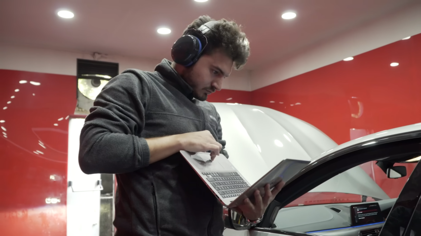 Technician Using a Laptop While Performing Dyno Testing on A BMW in A Garage