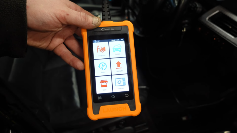 A Mechanic Holds a Handheld Diagnostic Tool, Showcasing the Essential Equipment Used for Accurate BMW Maintenance and Troubleshooting