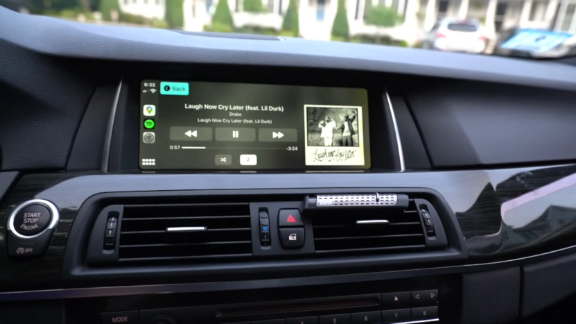 The Image Shows a BMW Infotainment Screen Using Apple CarPlay, Displaying Music Controls for A Song by Drake, with Apps Like Spotify and Google Maps Visible