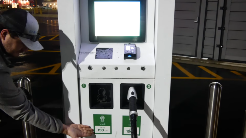 Man Using an Electric Vehicle Charging Station at Night