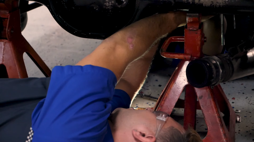 A Mechanic Works Underneath a European Car on A Lift, Demonstrating the Hands-On Attention Required to Follow Proper Maintenance Schedules for High-Performance Vehicles