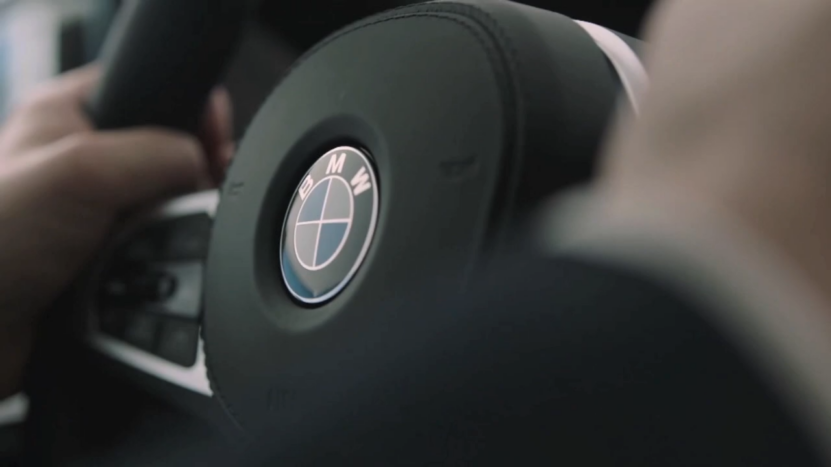 Close-Up of A Driver’s Hand on A BMW Steering Wheel, Focusing on Fine-Tuning Vehicle Settings