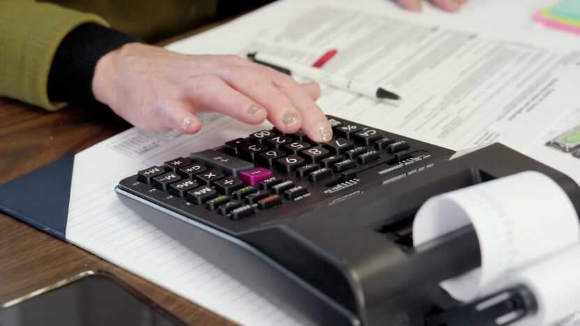 A Person Calculating the Realistic Valuation and Pricing of BMW Vehicles Using a Calculator and Documents