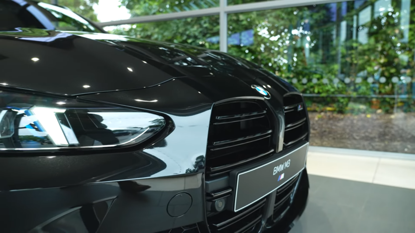 Front View of A Black 2025 BMW M3 in A Showroom with A Reflective Hood and Visible BMW Logo and M3 Badge