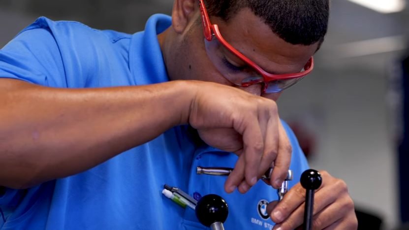 A European Car Mechanic Focuses Intently While Working with Specialized Tools, Highlighting the Importance of Precision and Expertise in Servicing High-End Vehicles