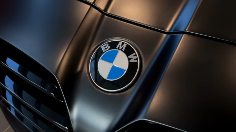 Close-Up of The Bmw Logo on The Hood of A 2025 BMW M3, Accentuated by The Sleek, Dark Finish of The Car