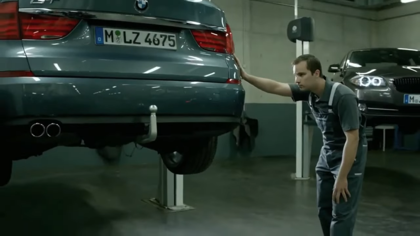 A Mechanic Inspecting a BMW in A Repair Shop, Focusing on Potential Cosmetic Damage