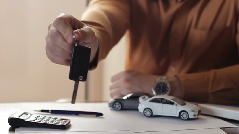 A Person Holding a Car Key with A Calculator and Small Car Models on The Table, Symbolizing BMW Insurance Coverage Options