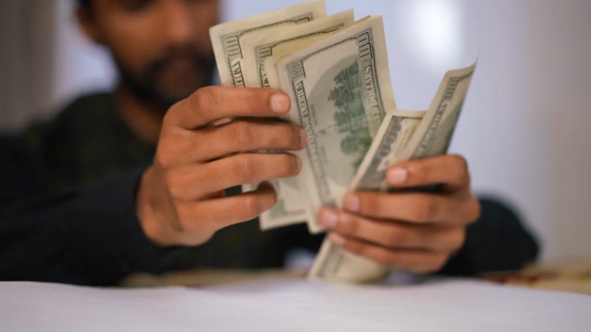 A Person Counting a Stack of Hundred-Dollar Bills, Representing Financial Concerns After an Accident