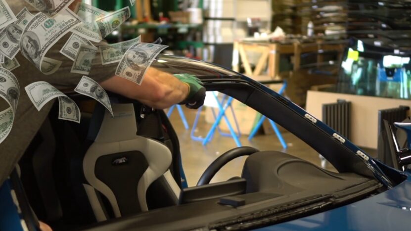 A Technician Installs a New Windshield on A BMW, with Dollar Bills Superimposed to Highlight the Cost of The Replacement