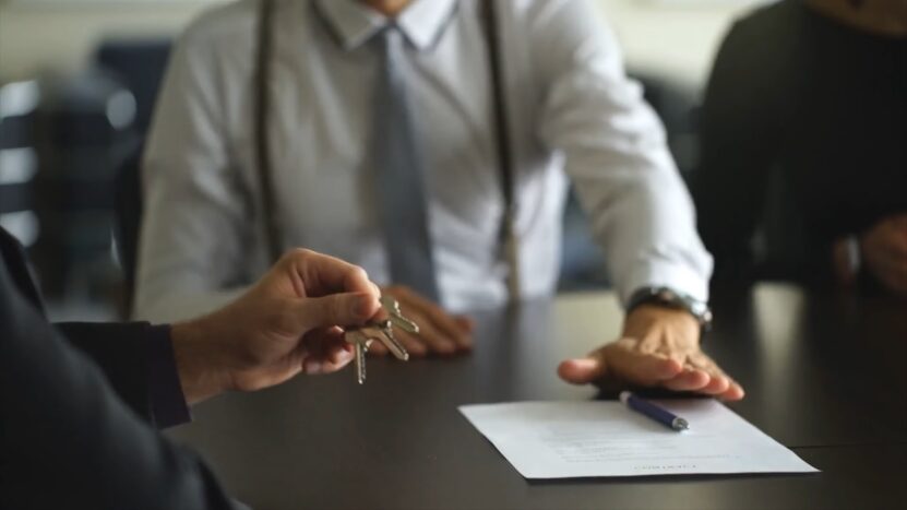 A Person Hands Over Car Keys to Another, Possibly After Signing a Lease Agreement