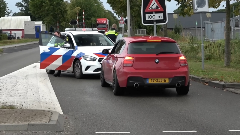 Police Officers Inspecting a Red BMW and Another Vehicle After a Minor Car Accident on A Road