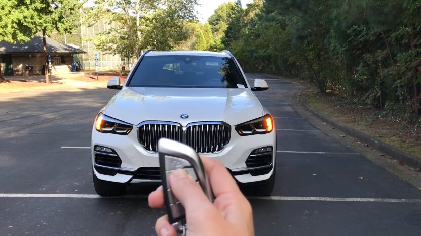 Person Using a Remote to Start a White BMW Parked in An Outdoor Lot