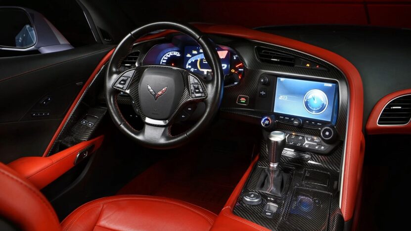 Sports car interior featuring a red and black color scheme, carbon fiber accents